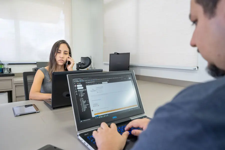 Integrantes da equipe da Arnoldi em uma ligação de trabalho, com notebooks abertos na mesa