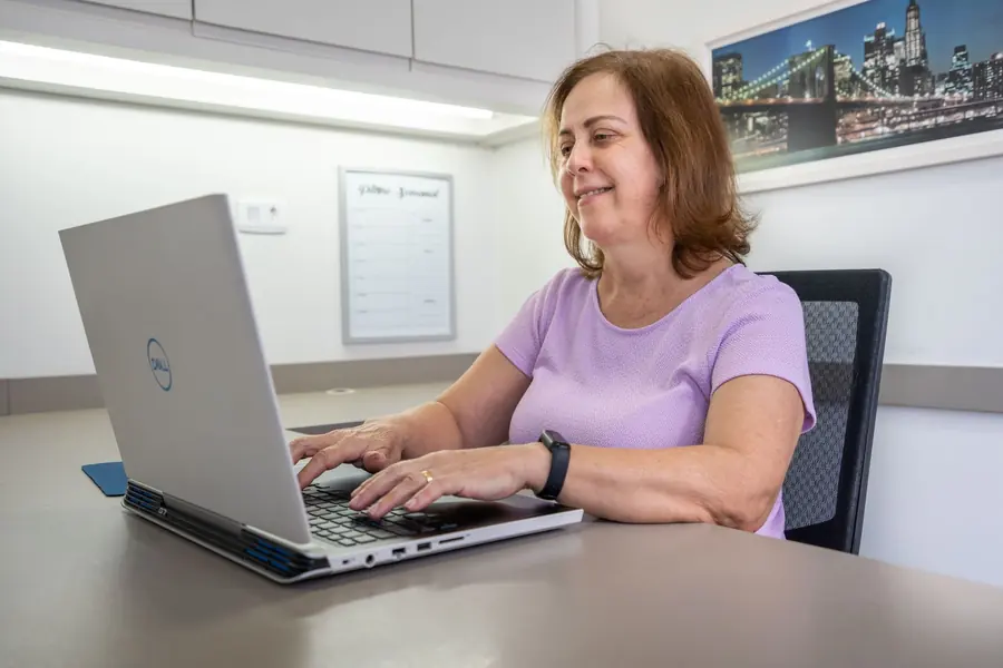 Integrante da equipe da Arnoldi digitando no notebook, no escritório