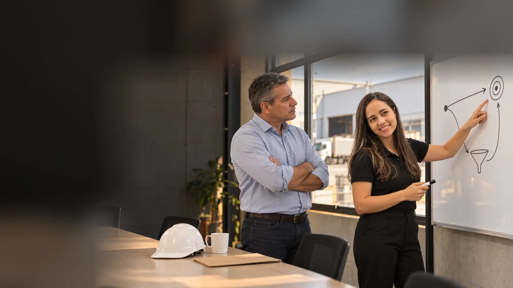 Lari aponta dois caminhos desenhados no quadro branco para um diretor comercial de braços cruzados, em sala de reunião de um galpão industrial