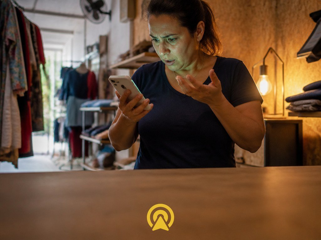 Empresária olhando assustada para o celular ao descobrir que o WhatsApp da loja foi clonado