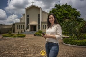 Empresária filmando conteúdo com celular em frente à Igreja Matriz de São Pedro em Engenheiro Coelho