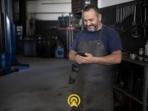 Dono de oficina mecanica olhando o celular com expressao aliviada, representando a duvida se e preciso trocar de WhatsApp para automatizar o atendimento